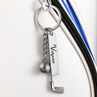 Personalized golf keychain attached to a golf bag zipper with engraved name plate and golf charms
