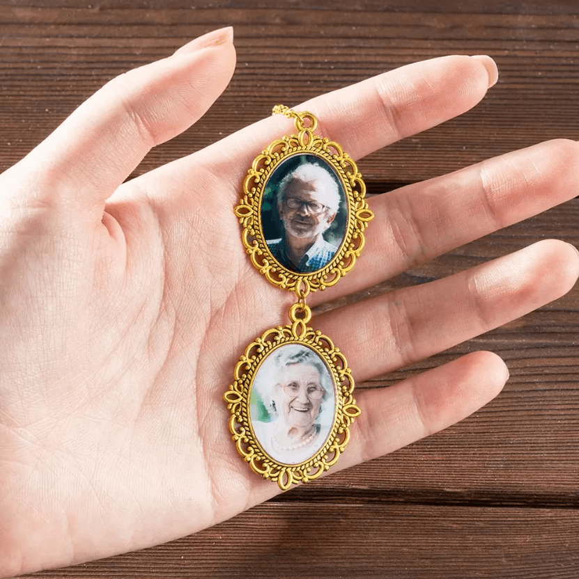 A hand holding a gold double-frame ornament with photos of an older man and woman, used for a graduation hat tassel.