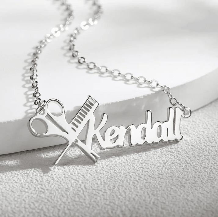 Silver personalized hairdresser necklace with the name Kendall, featuring a scissors and comb design, displayed on a white background.