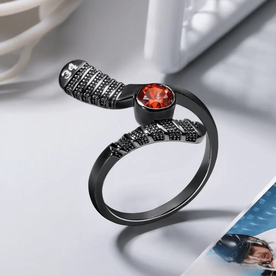 Black matte hockey stick-shaped ring with a fiery orange gemstone and number '34' detail, resting beside a photo of a hockey player.