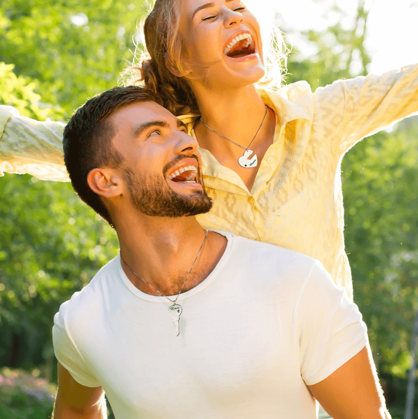 Happy couple wearing personalized "Key to My Heart" necklaces with custom names and birthstones. Heart and key pendants for him and her, enjoying time outdoors.