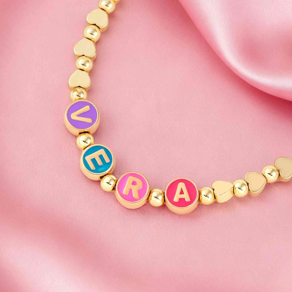 Close-up of personalized name necklace with colorful enamel letters and gold beads