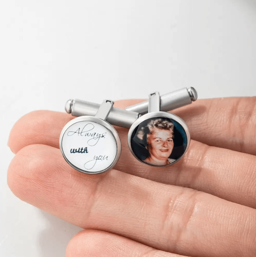 Customizable silver cufflinks held in hand; one with 'Always with you' engraving, the other with an elderly woman's photo.