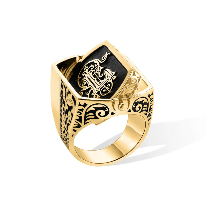 Elegant gold flip ring with a black inlay featuring intricate double initials, set against a white background.