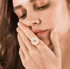 Smiling woman showcasing a gold spinner ring with engraved names and a central purple birthstone, highlighting its unique and customizable design.