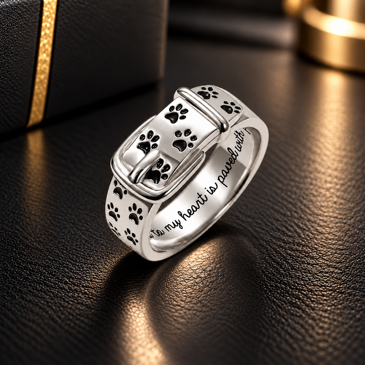 Personalized paw print collar ring in 925 sterling silver, featuring a buckle design, black paw prints and engraved pet memorial message on black leather.