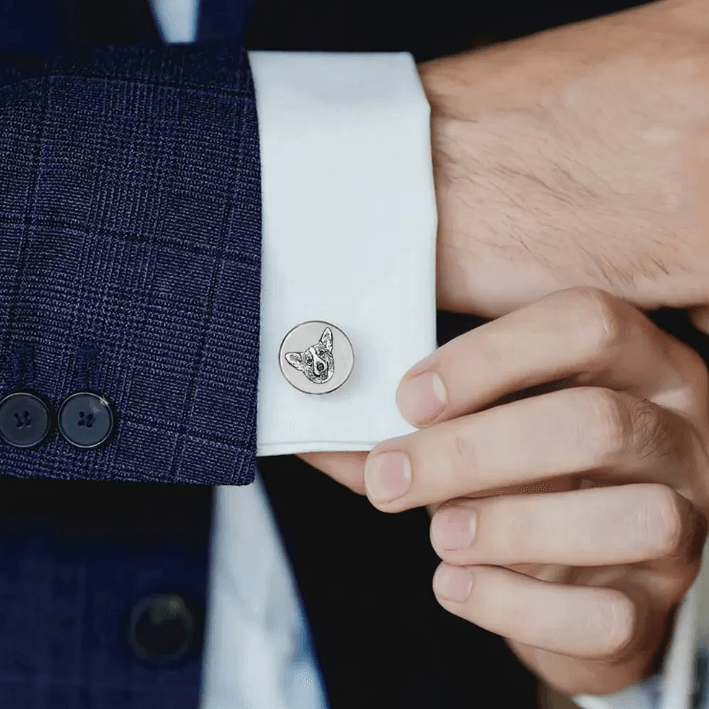 Silver cufflink with engraved French Bulldog portrait worn on a white shirt sleeve with a navy blue suit jacket.