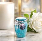 Personalised mini cremation urn with photo engraving displayed beside a white rose and candle for remembrance.