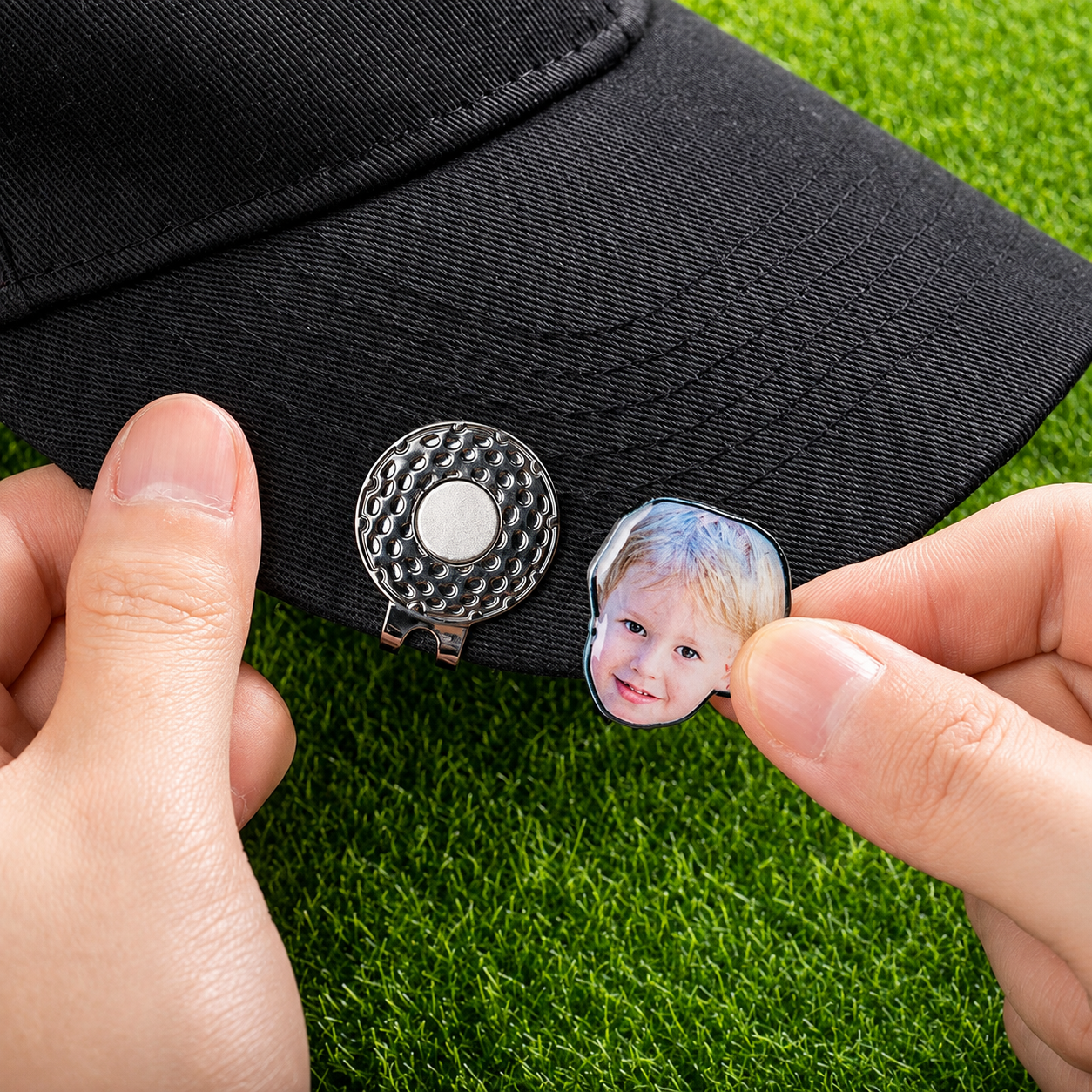 Custom child photo golf ball marker being attached to magnetic hat clip on black cap