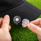 Custom child photo golf ball marker being attached to magnetic hat clip on black cap