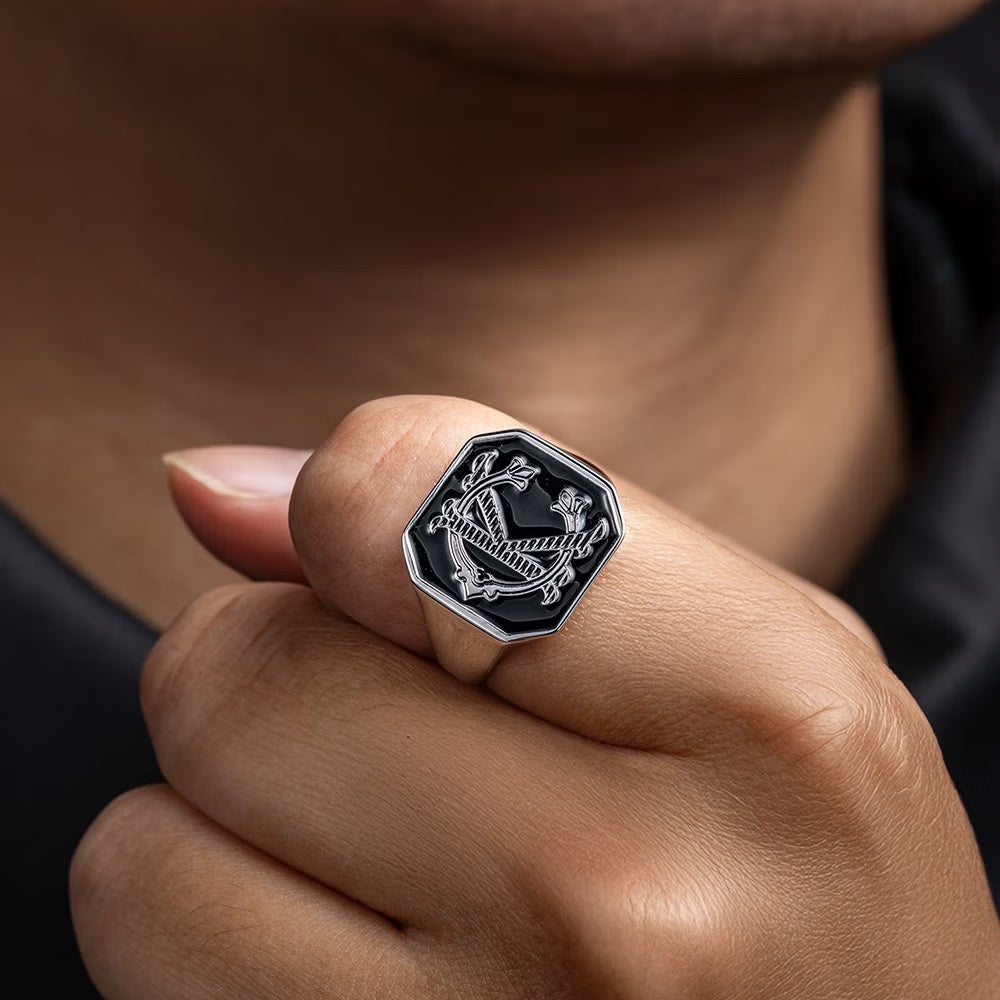 Silver tone custom engraved double initials signet ring with black monogram face worn on a hand.
