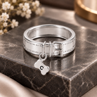 Personalized silver pet collar ring with buckle design and engraved bone charm featuring the letter C, displayed on a dark marble stand.
