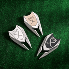 Three personalized stainless steel golf marker divot repair tools with custom monograms reading "DAD," "CHRIS," and "BEN," displayed on green turf.