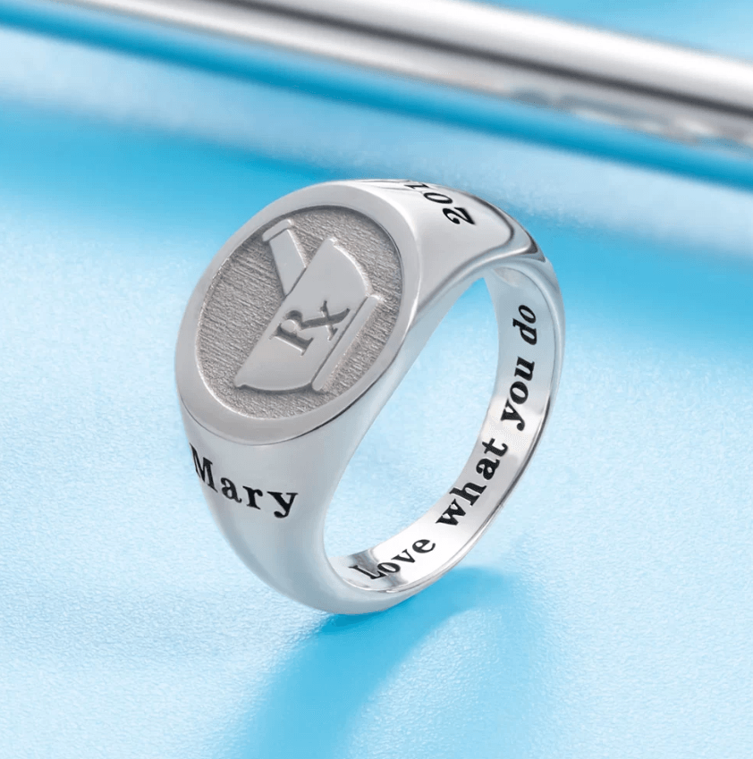 Silver ring with an engraved medical symbol (Rx) and the name "Mary." The inside of the band is inscribed with the phrase "Love what you do."