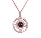 Rose gold pendant with a circular design featuring Roman numerals, a black central gemstone, and sparkling diamonds on a fine chain.