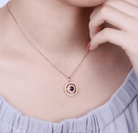 Close-up of a person wearing a rose gold pendant with a black gemstone and Roman numerals, highlighting the intricate design on a delicate chain.