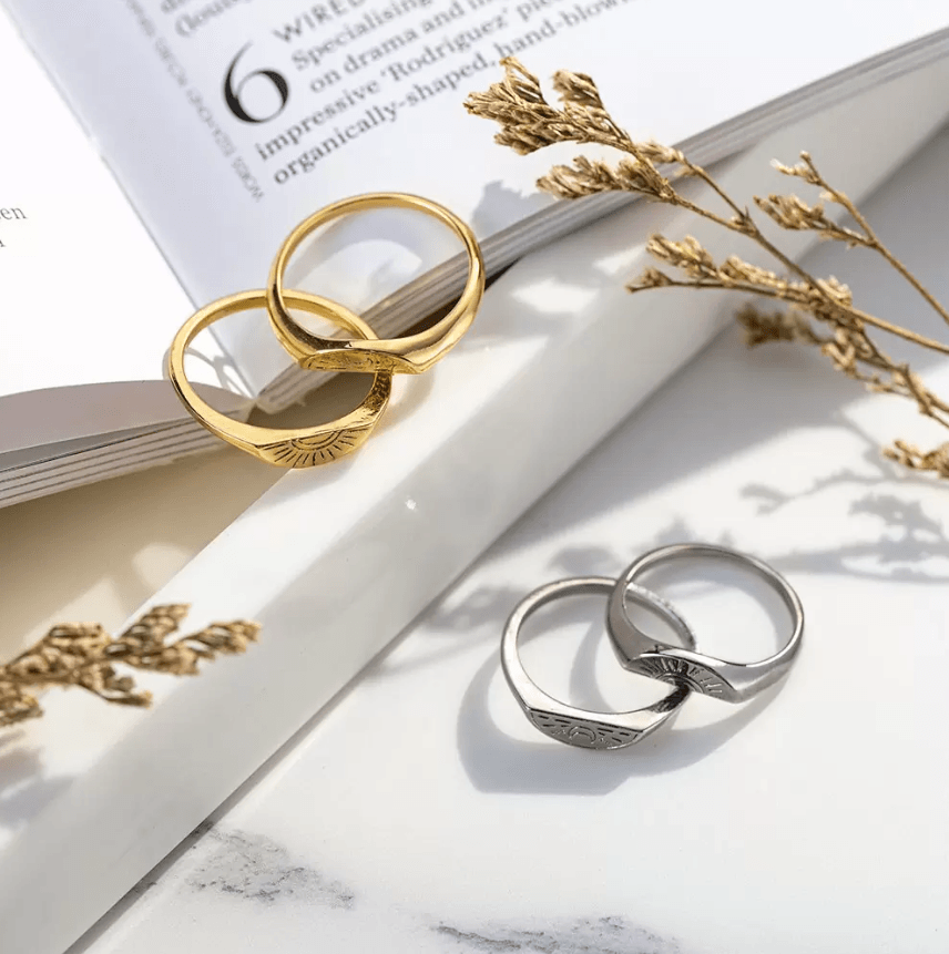 Interlinked gold and silver rings with sun and moon engravings rest on an open book.