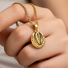 Gold horse hoof charm necklace held in hand showing pendant detail