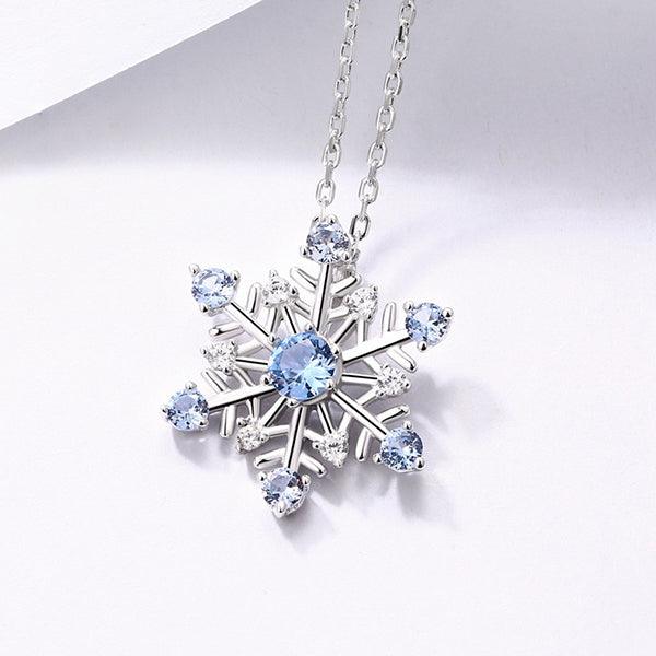 Elegant snowflake pendant necklace in pure silver with sparkling blue stones, perfect for Christmas and winter gifts, displayed on a delicate silver chain.
