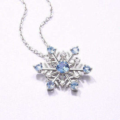 Elegant snowflake pendant necklace in pure silver with sparkling blue stones, perfect for Christmas and winter gifts, displayed on a delicate chain.