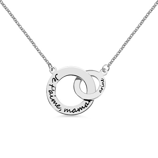 A silver necklace featuring two interlocking circles, one larger and one smaller, engraved with the words "Je t'aime, maman" and "aime."