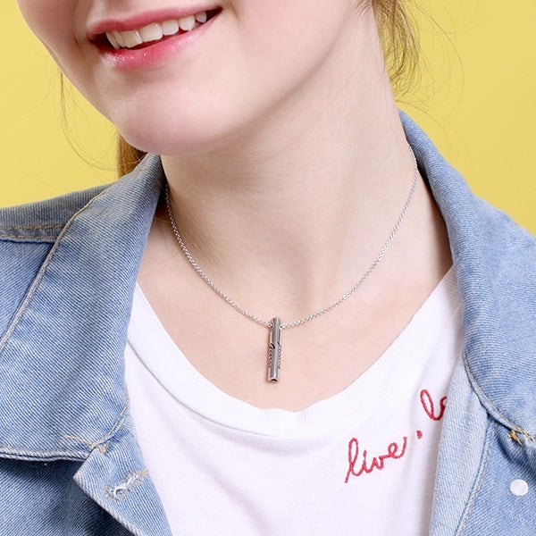 Smiling woman wearing a personalized sterling silver bar pendant necklace, engraved with names, paired with a white t-shirt and denim jacket.