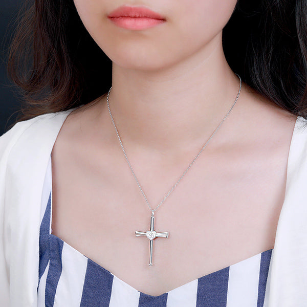 Woman wearing a silver baseball bat cross necklace with a jersey number, styled with a casual striped outfit.