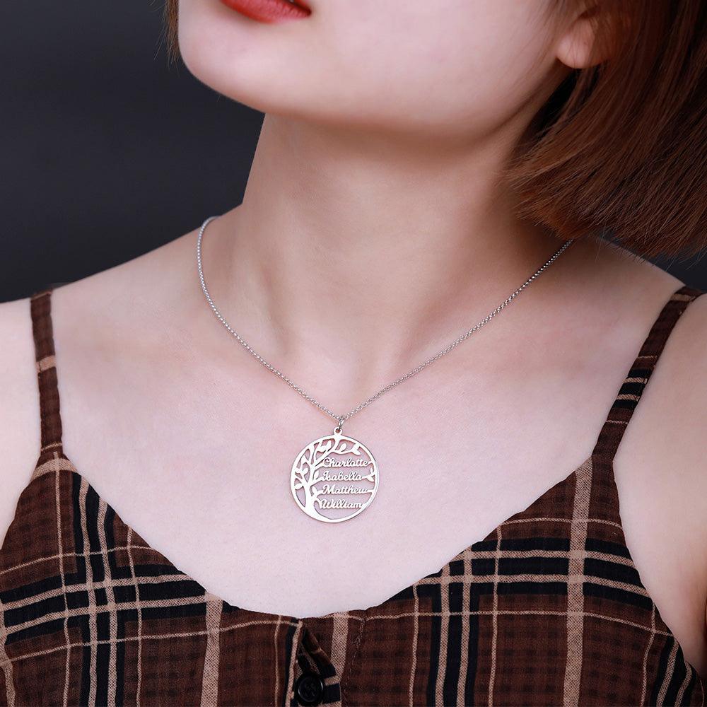 A woman wearing a silver necklace with a round pendant featuring a tree design and names "Charlotte, Isabella, Matthew, William," against a checkered brown top.