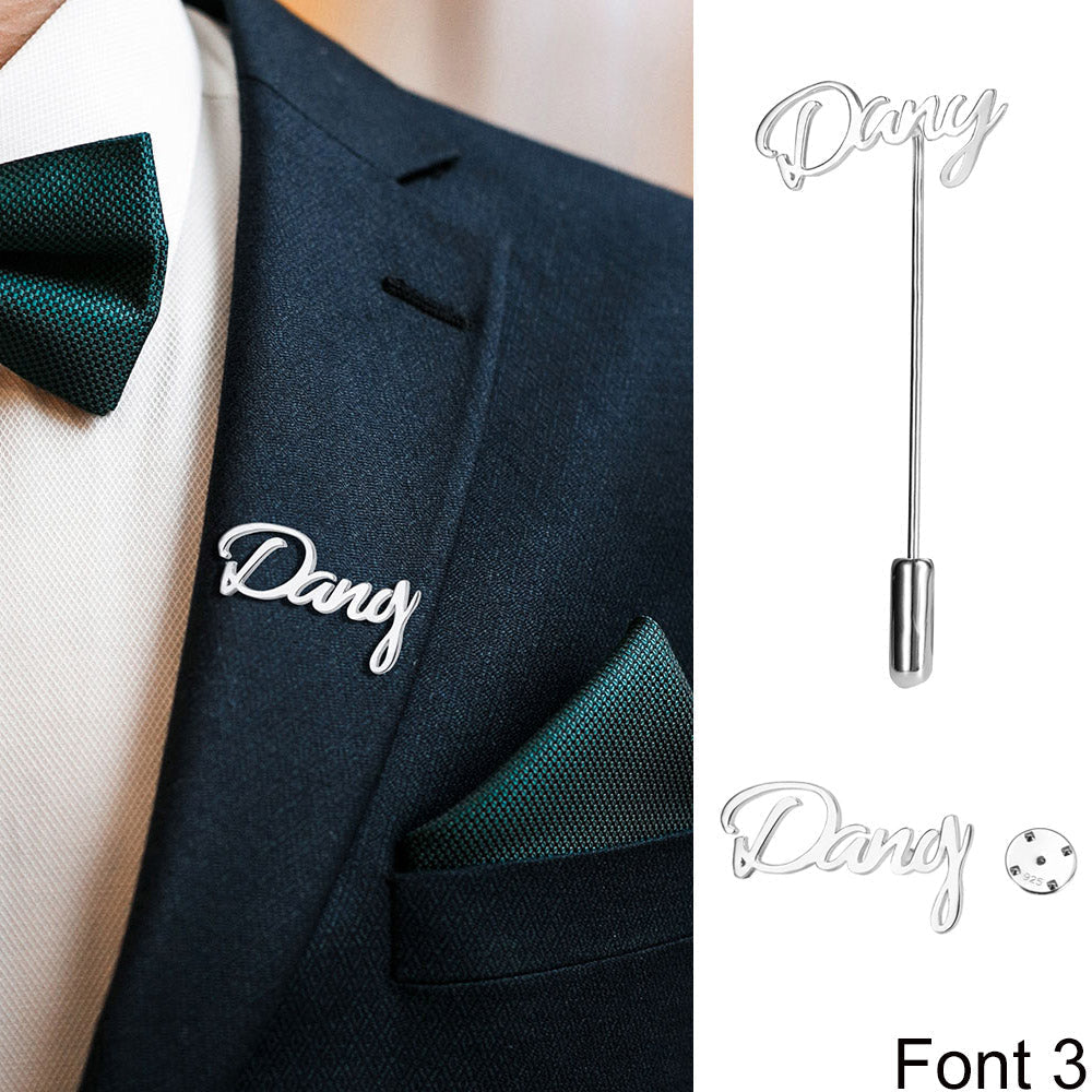 Suit with 'Dany' silver script lapel pin, white shirt, and green tie and pocket square.