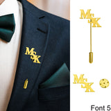 Suit with 'MSK' gold monogram lapel pin, white shirt, and green tie and pocket square.