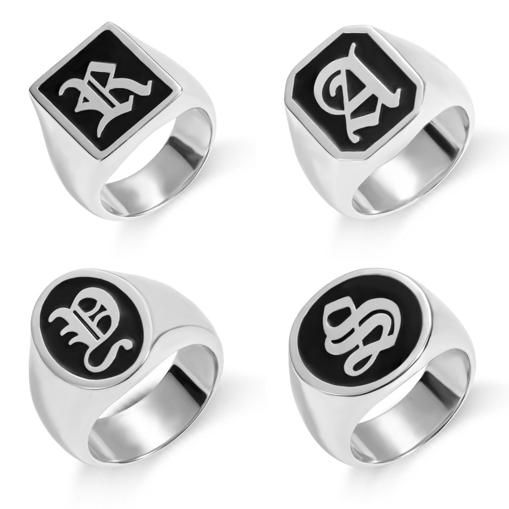 Four sterling silver signet rings with black enamel, each featuring a different stylized old English initial: 'R', 'A', intertwined 'E' and 'L', and 'S' on a white background.
