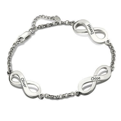 A silver bracelet with three infinity symbols, each engraved with a name: "Oliver," "Chloe," and "Daniel." The bracelet has a chain link design and a clasp.