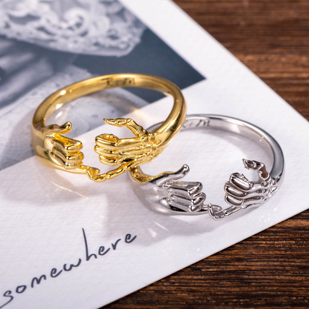 Gold and silver pinky promise rings lying on a letter with the word 'somewhere' printed below.