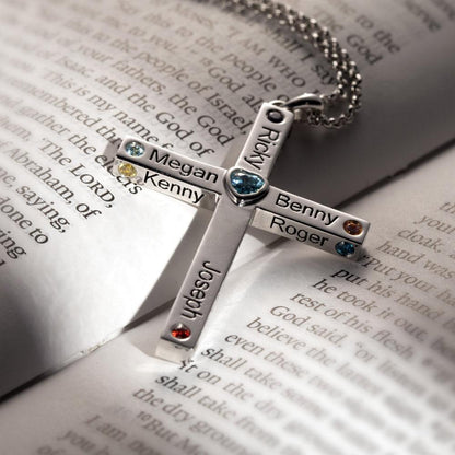 Personalized heart cross necklace with names and birthstones on a silver chain, placed on an open Bible, showcasing faith and love.