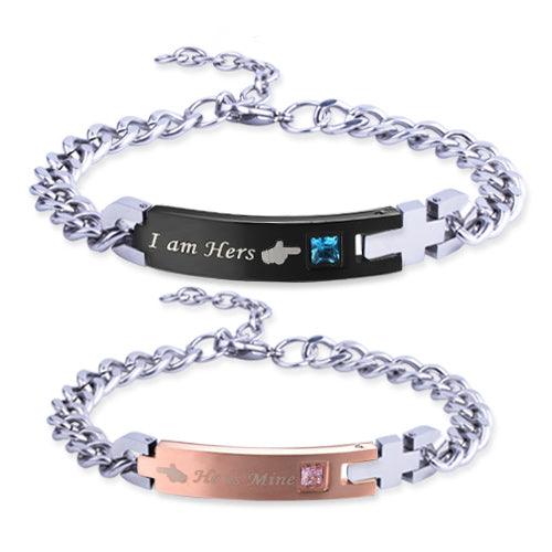 Two stainless steel bracelets, one black stating "I am Hers" and one rose gold stating "He is Mine," with rhinestones.