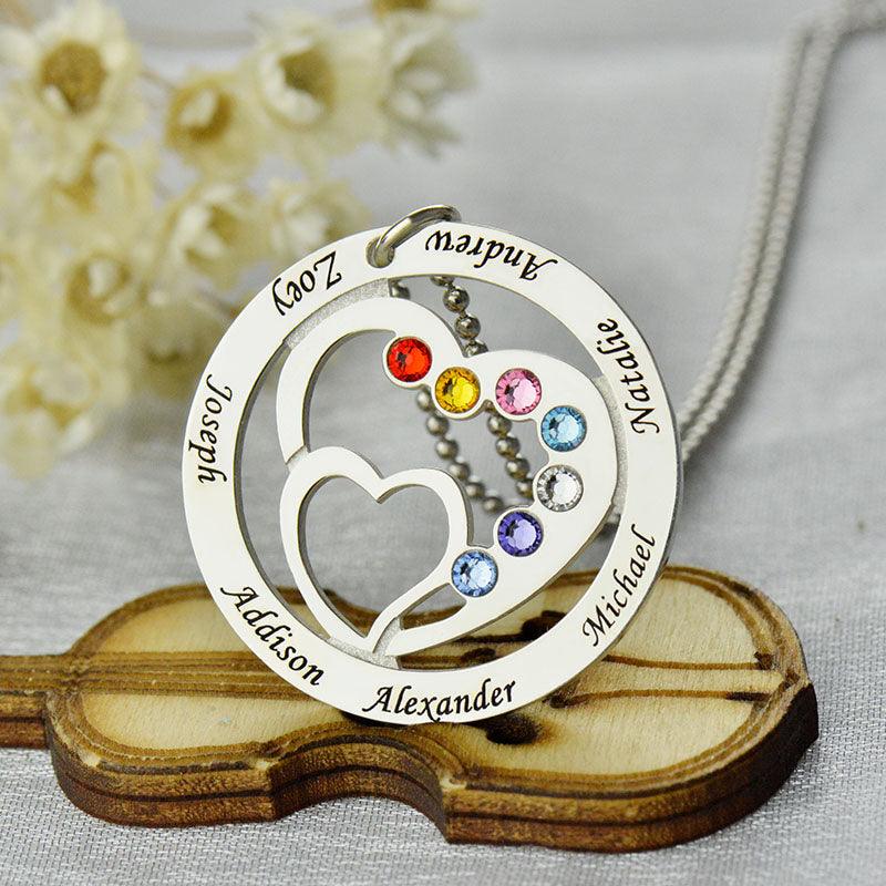 A silver heart-in-heart pendant with birthstones and names: Addison, Alexander, Joseph, Zoey, Andrew, Michael, Natalie. The pendant lies on a small wooden violin.