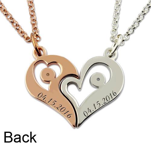 The back of a pair of complementary heart-shaped pendants, one in rose gold and one in silver, both inscribed with the date "04.15.2016," attached to matching chains.
