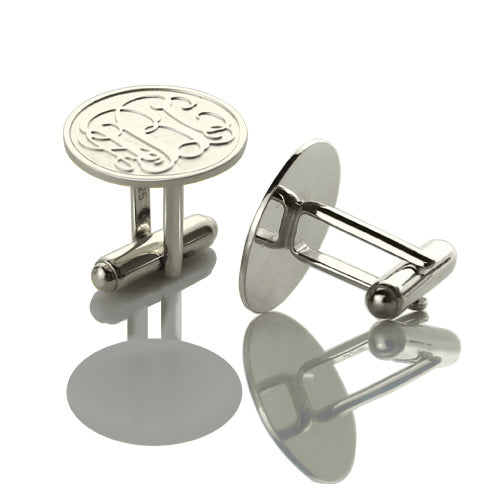 Silver cufflinks with the monogrammed letters "ABC" on a reflective surface.