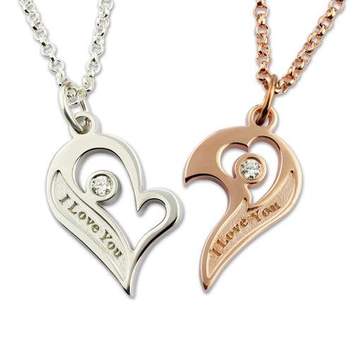 A pair of complementary heart-shaped pendants, one in silver and one in rose gold, each with a gemstone and "I Love You" inscription, attached to matching chains.