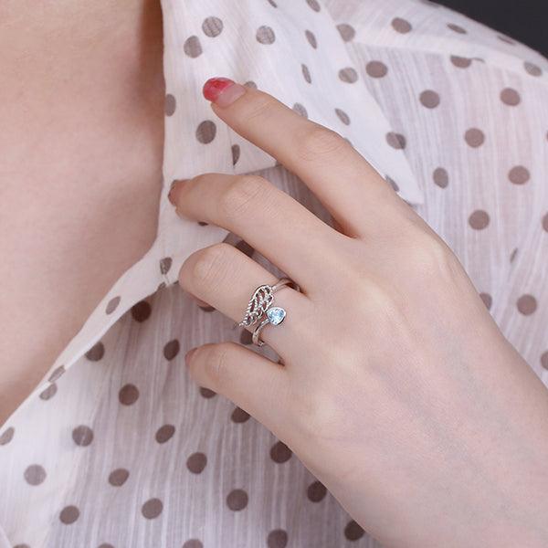 Hand wearing a silver angel wing ring with blue stone, matching a polka dot blouse BD37-4 - 600 x 600px