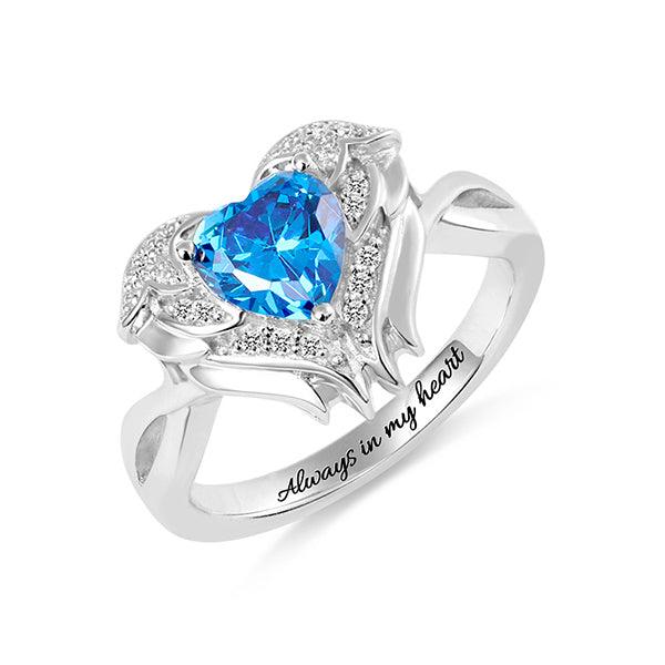 Silver angel wing ring with a blue heart gemstone and 'Always in my heart' engraving on a white background CG274-1 - 600 x 600px