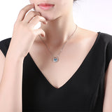 Elegant woman wearing a black V-neck dress with a silver horseshoe necklace featuring a blue stone.