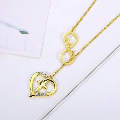 Gold Infinity Heart Name Necklace with Custom Birthstone, featuring a heart and cross design, personalized with the name "Hayley" and sparkling birthstones, displayed on a white surface.