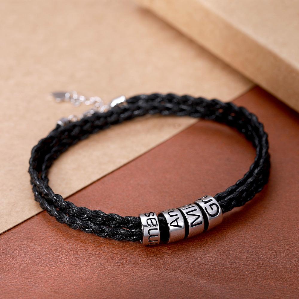 Black braided bracelet with silver beads engraved with "Mama," "Ang," and "Gi" on a brown background.