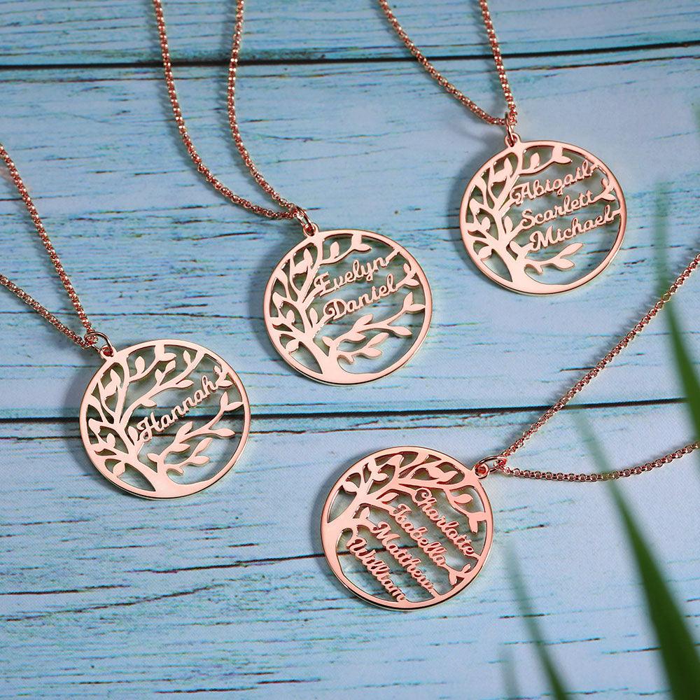 Four rose gold necklaces with round pendants featuring a tree design and names: "Hannah," "Evelyn Daniel," "Abigail Scarlett Michael," and "Charlotte Isabella Matthew William," on a blue wooden background.