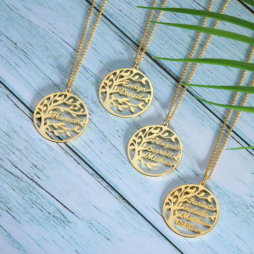 Four gold necklaces with round pendants featuring a tree design and names: "Hannah," "Evelyn Daniel," "Abigail Scarlett Michael," and "Charlotte Isabella Matthew William," on a blue wooden background.