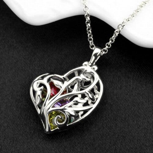 A heart-shaped silver pendant with an intricate tree design, featuring multicolored gemstones, hanging on a delicate silver chain.