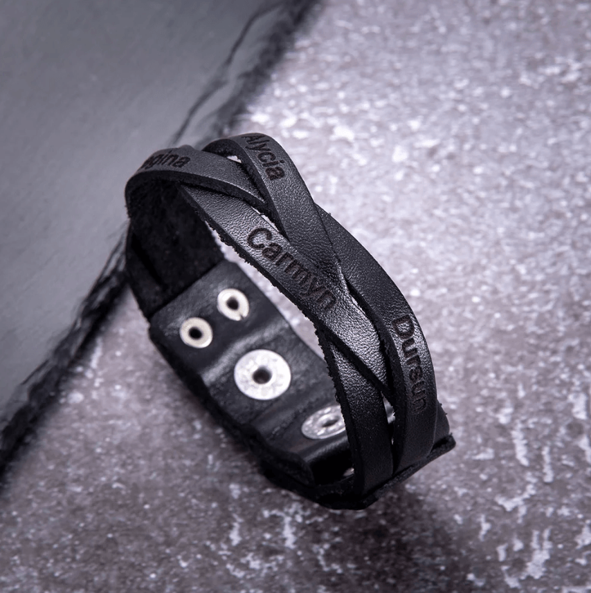Black leather bracelet with names Alina, Camryn, Duran on a frosty surface.