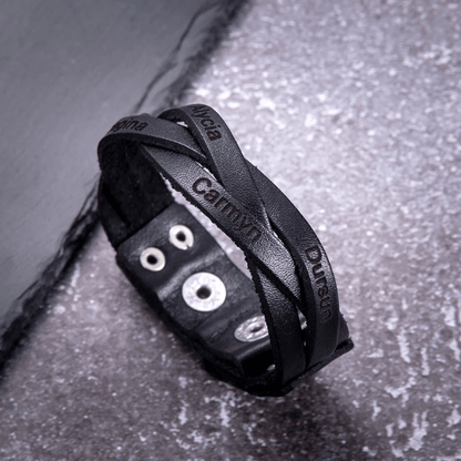 Black engraved leather bracelet with names Alina, Camryn, and Duran, on a snowy surface.
