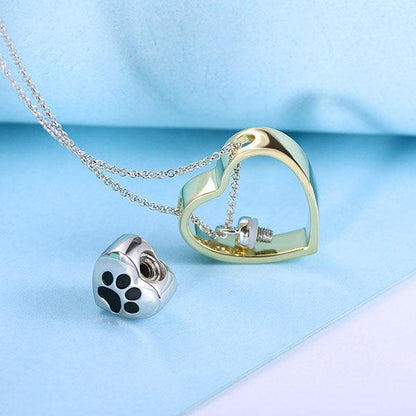 Gold heart-shaped pendant with an open design on a silver chain, accompanied by a separate paw print charm